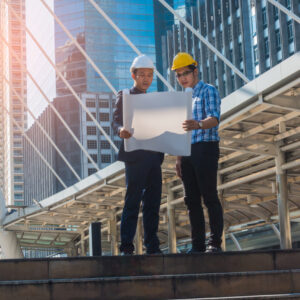 Young businessman with young engineers looking at a project on the construction site.
